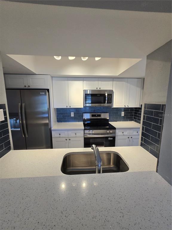 4836 Onyx Lane, Unit B New Port Richey, FL 34652 - Photo 5 of 13 a kitchen with stainless steel appliances a stove a sink a microwave a refrigerator and cabinets