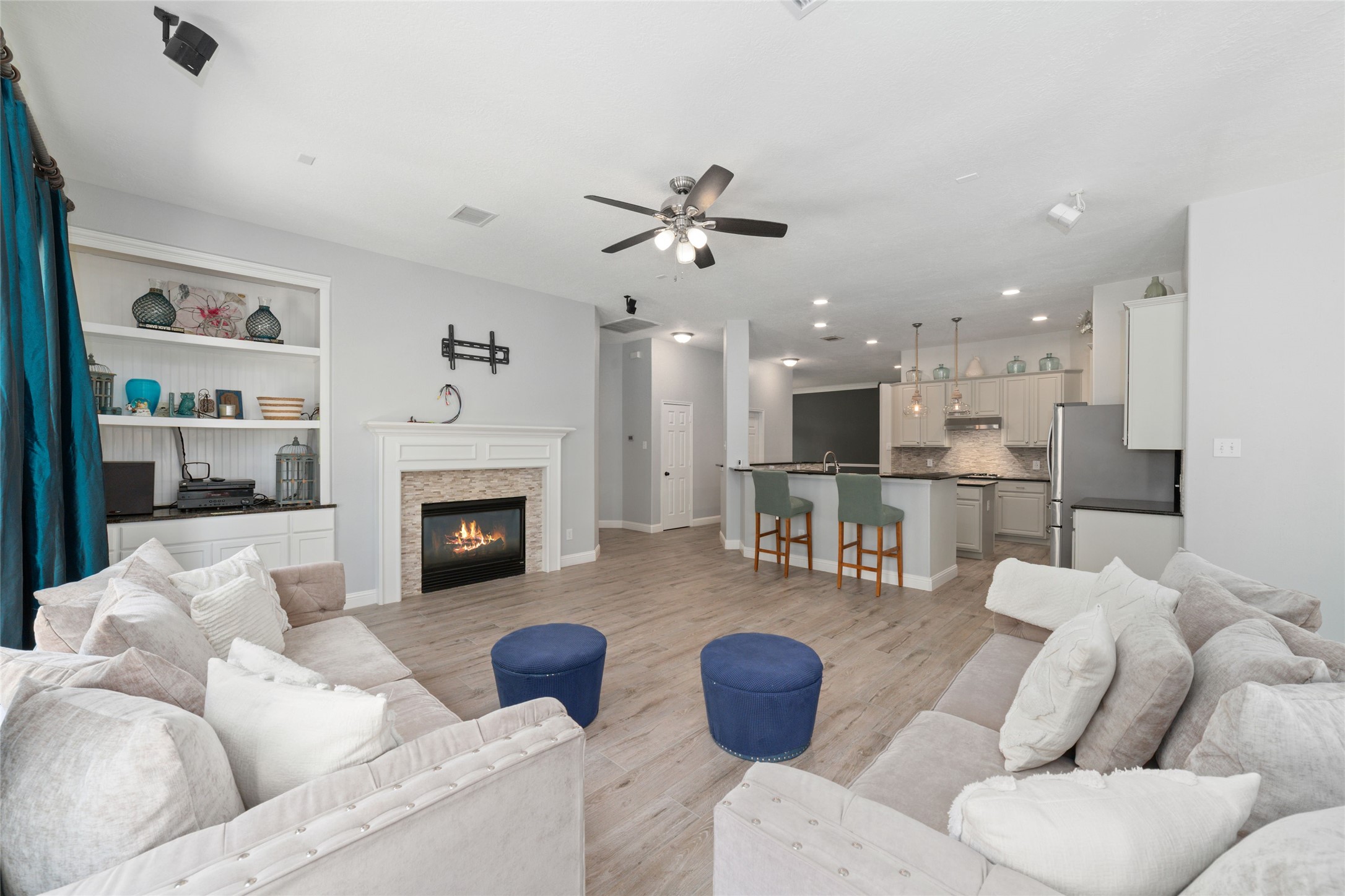 24203 Moon Ridge Court Katy, TX 77494 - Photo 21 of 43 This spacious living area features a cozy fireplace and an open-concept design. The room is well-lit, with neutral tones and stylish built-in shelving, creating a warm and inviting atmosphere for entertaining or relaxing.