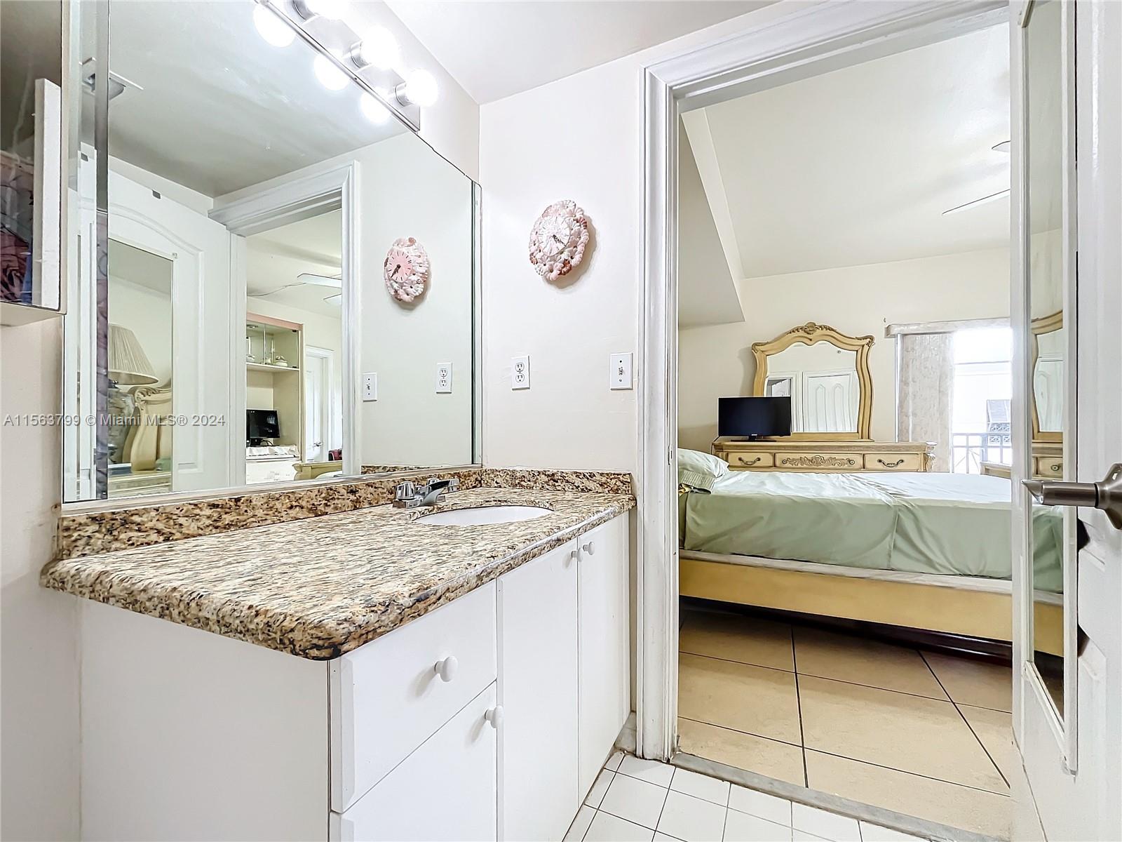 120 South Douglas Road, Unit 302 Miami, FL 33134 - Photo 15 of 28 a bedroom with a granite countertop sink and a mirror