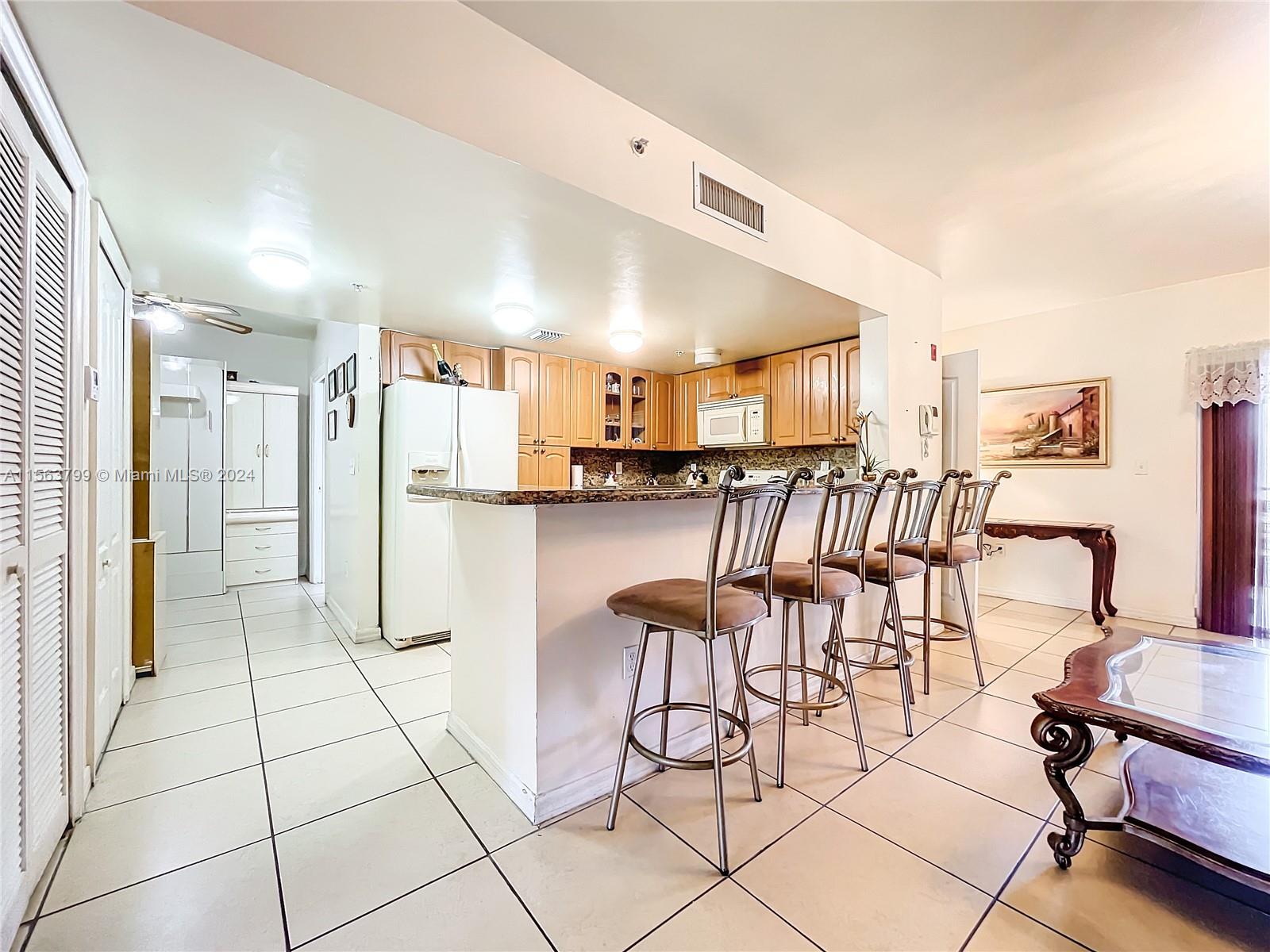 120 South Douglas Road, Unit 302 Miami, FL 33134 - Photo 9 of 28 a kitchen with stainless steel appliances kitchen island granite countertop a refrigerator and white cabinets