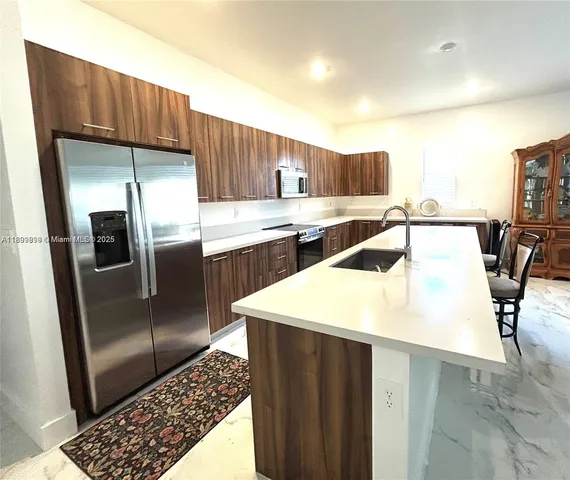 a kitchen with kitchen island a counter top space cabinets and stainless steel appliances