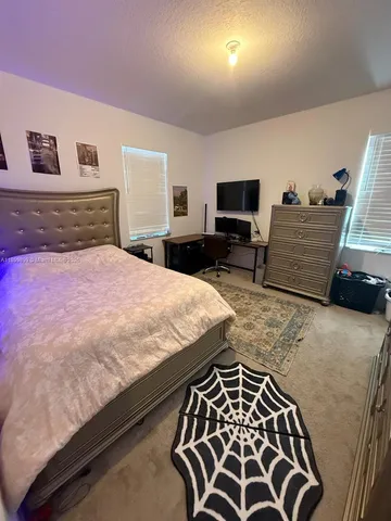 a bedroom with a bed and a lamp on dresser