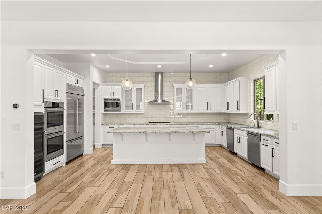 Kitchen with white cabinetry, glass insert cabinets, a kitchen breakfast bar, decorative light fixtures, and recessed lighting