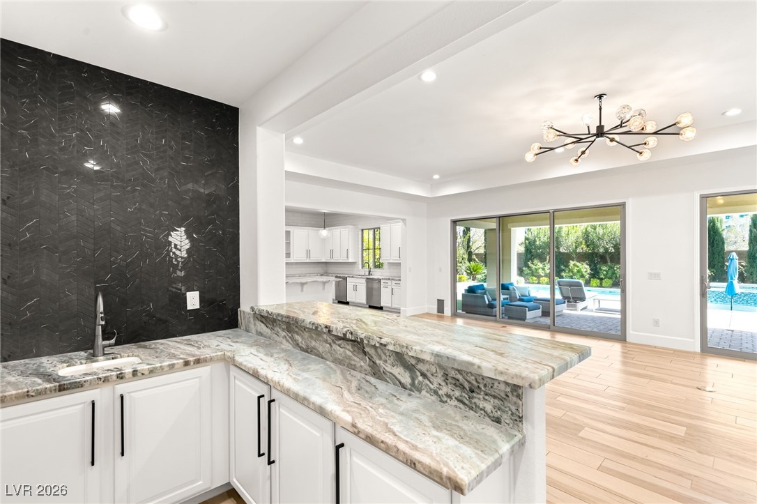 4039 Villa Rafael Drive Las Vegas, NV 89141 - Photo 18 of 45 Kitchen featuring white cabinets, light stone counters, a chandelier, light wood-type flooring, and a peninsula