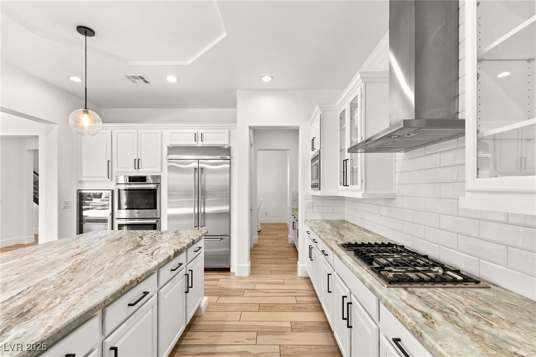 4039 Villa Rafael Drive Las Vegas, NV 89141 - Photo 21 of 45 Kitchen featuring white cabinetry, light stone countertops, hanging light fixtures, built in appliances, and wood tiled floors