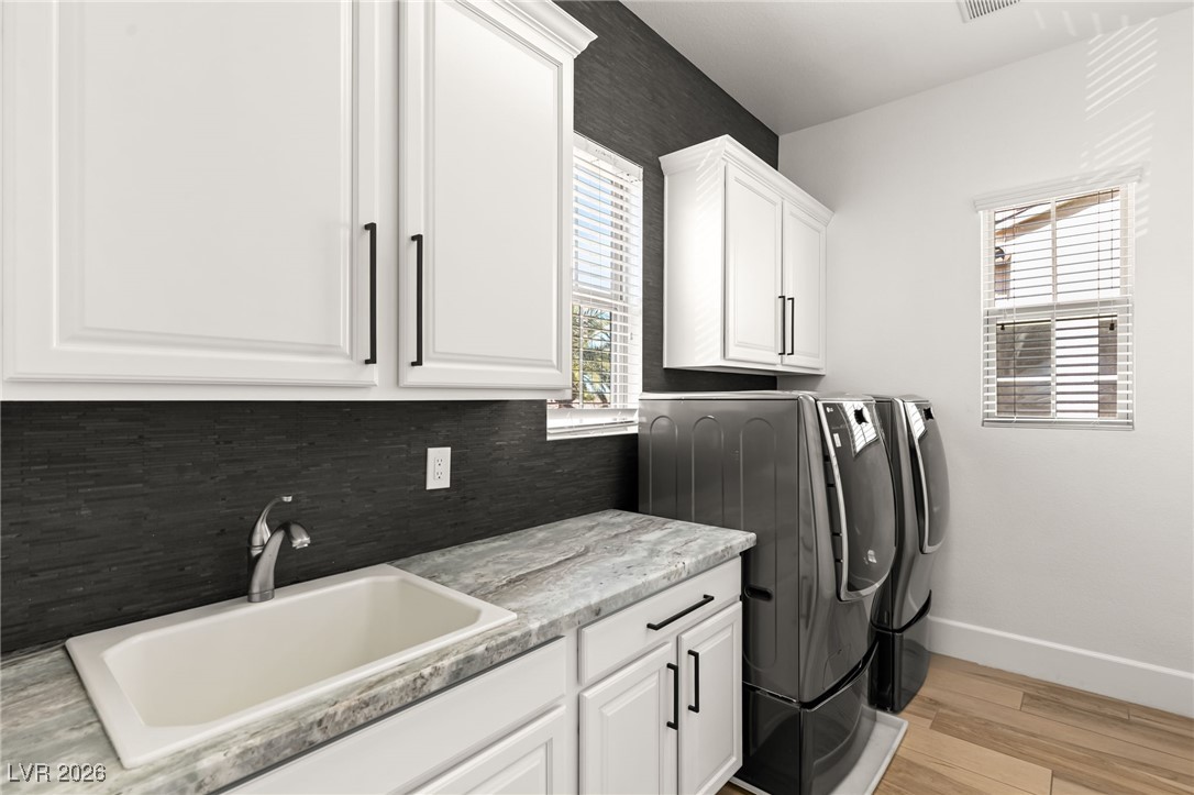 4039 Villa Rafael Drive Las Vegas, NV 89141 - Photo 33 of 45 Laundry area featuring washing machine and dryer, light wood-type flooring, and cabinet space