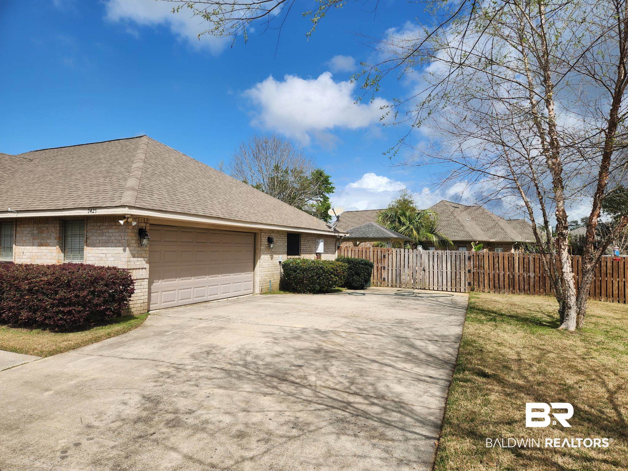 9425 Autauga Bend Daphne, AL 36526 - Photo 2 of 15 View of side of home with brick siding, concrete driveway, roof with shingles, and an attached garage