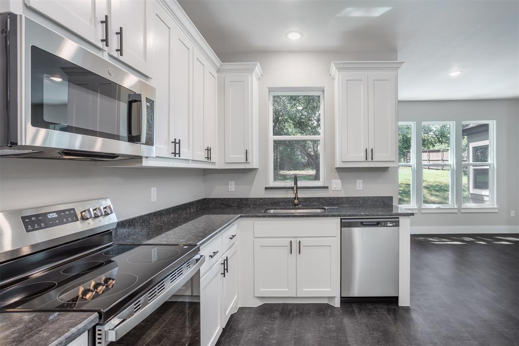 326 West Day Street Denison, TX 75020 - Photo 14 of 27 a kitchen with stainless steel appliances granite countertop a stove a sink and a microwave