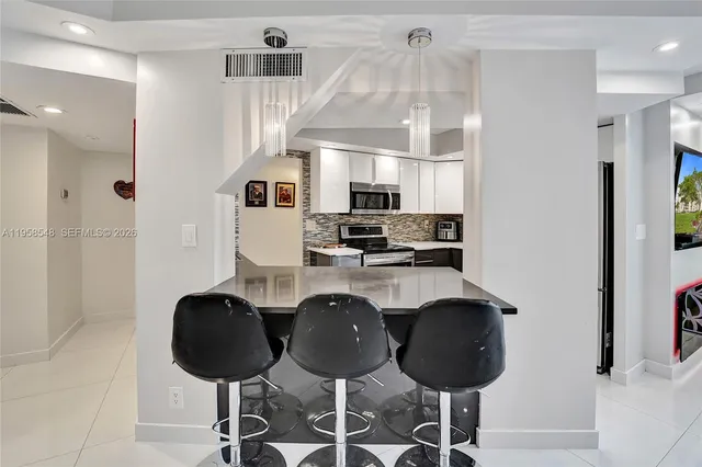 a kitchen with stainless steel appliances granite countertop a refrigerator a stove a sink dishwasher and white cabinets with wooden floor