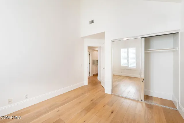 a view of an empty room with wooden floor and closet