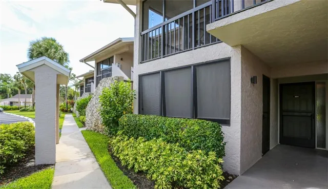 a view of a house with a small yard plants and large tree