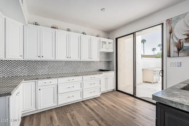 a large kitchen with a large counter top a sink stainless steel appliances and windows