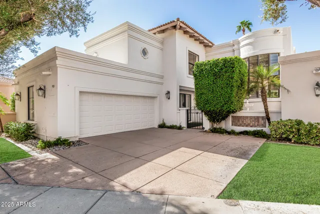 a view of a white house with a small yard plants and a large tree