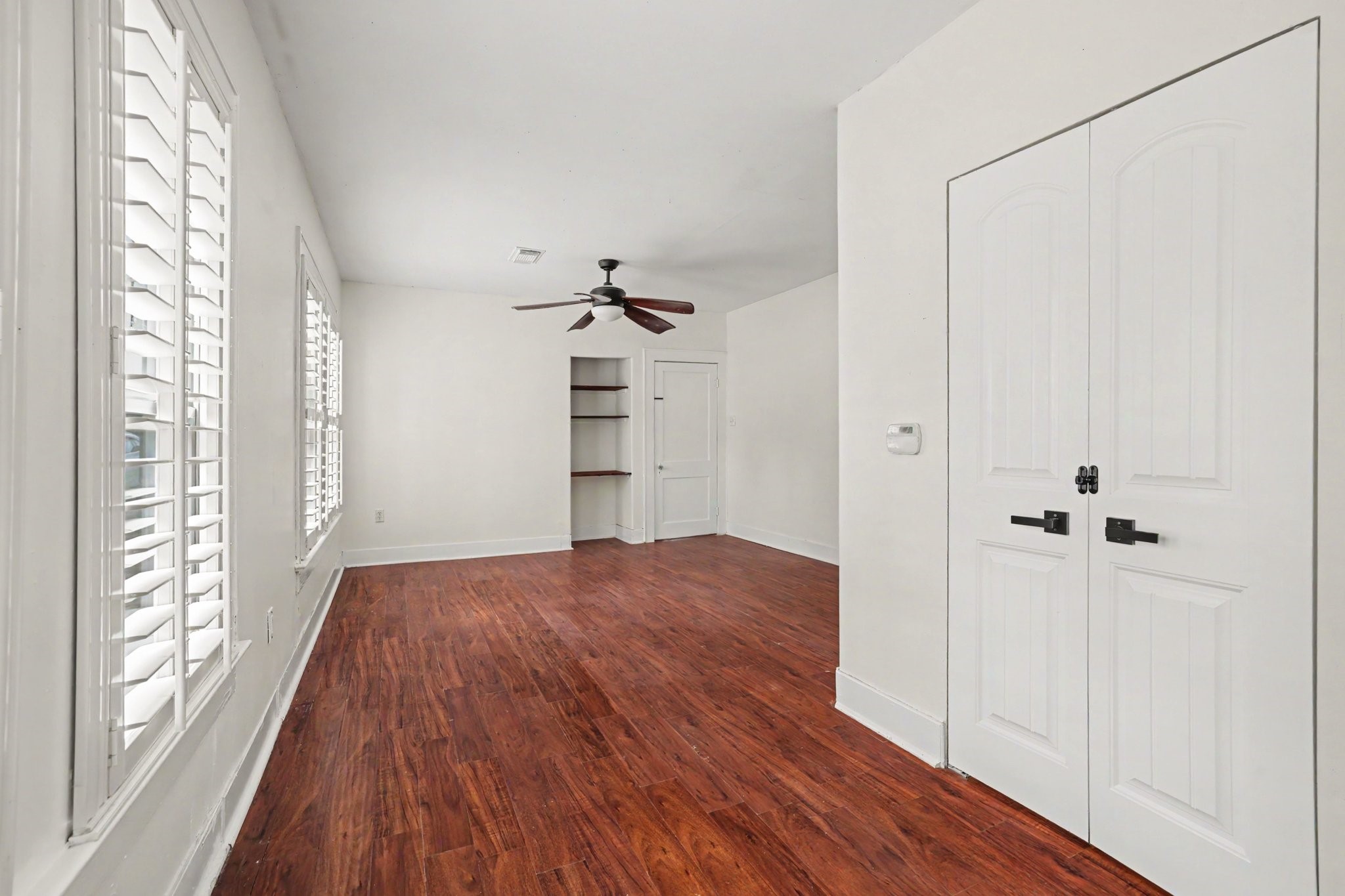 31730 Waller Tomball Road Waller, TX 77484 - Photo 27 of 50 Bright bedroom with vinyl flooring and large windows with shutters also features double doors leading to walk-in closet, and a built-in shelf.