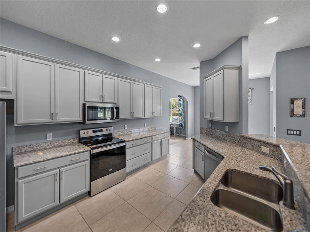 1124 Sawgrass Drive Winter Haven, FL 33859 - Photo 14 of 85 a kitchen with stainless steel appliances granite countertop a stove a sink and a refrigerator