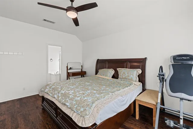 a bedroom with a bed a dresser and wooden floor