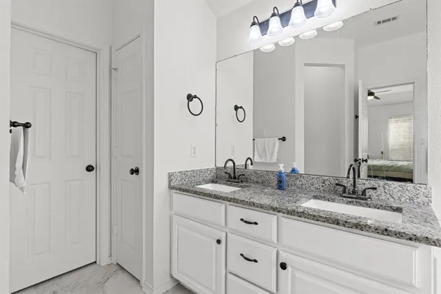 a bathroom with a granite countertop double vanity sink a mirror and a shower