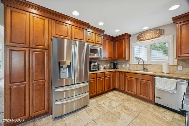 a kitchen with granite countertop stainless steel appliances a refrigerator cabinets and a sink