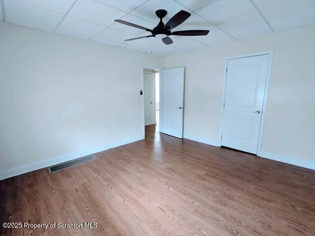 a view of a room with wooden floor and a ceiling fan