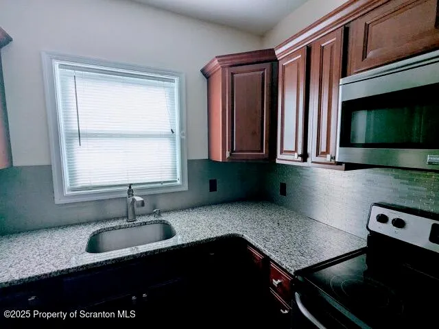 a kitchen with granite countertop a sink a stove and cabinets