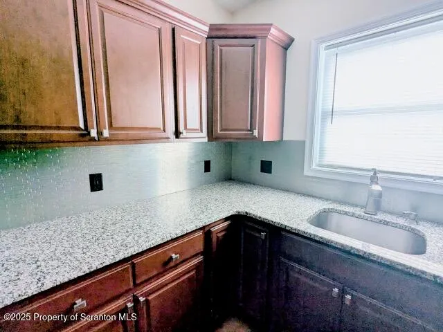 a kitchen with granite countertop a sink a window and cabinets
