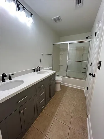 a bathroom with a double vanity sink a toilet and shower