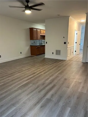 an empty room with wooden floor and kitchen view