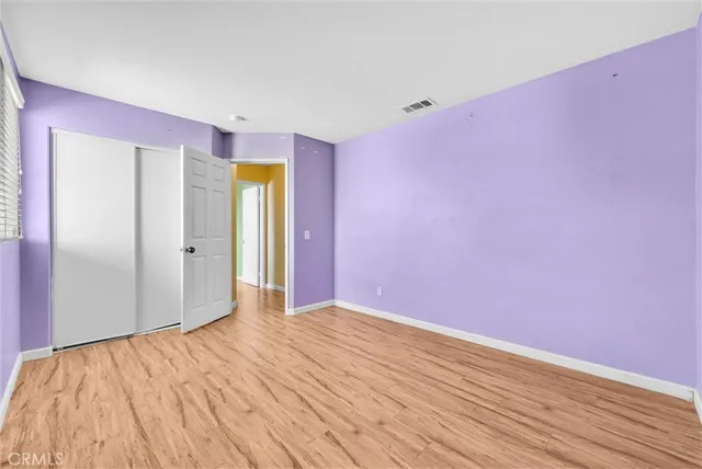 a view of empty room with wooden floor and bathroom