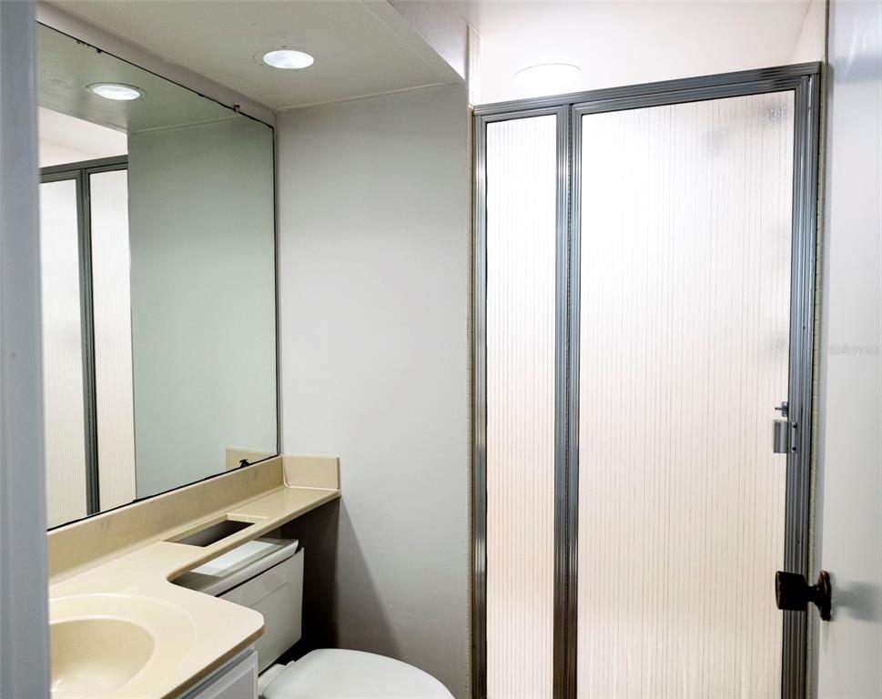 7100 Sunset Way, Unit 810 St. Pete Beach, FL 33706 - Photo 15 of 42 a bathroom with a sink a toilet a mirror and shower