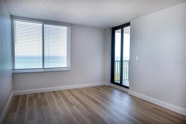 a view of a hallway with wooden floor and a bathroom