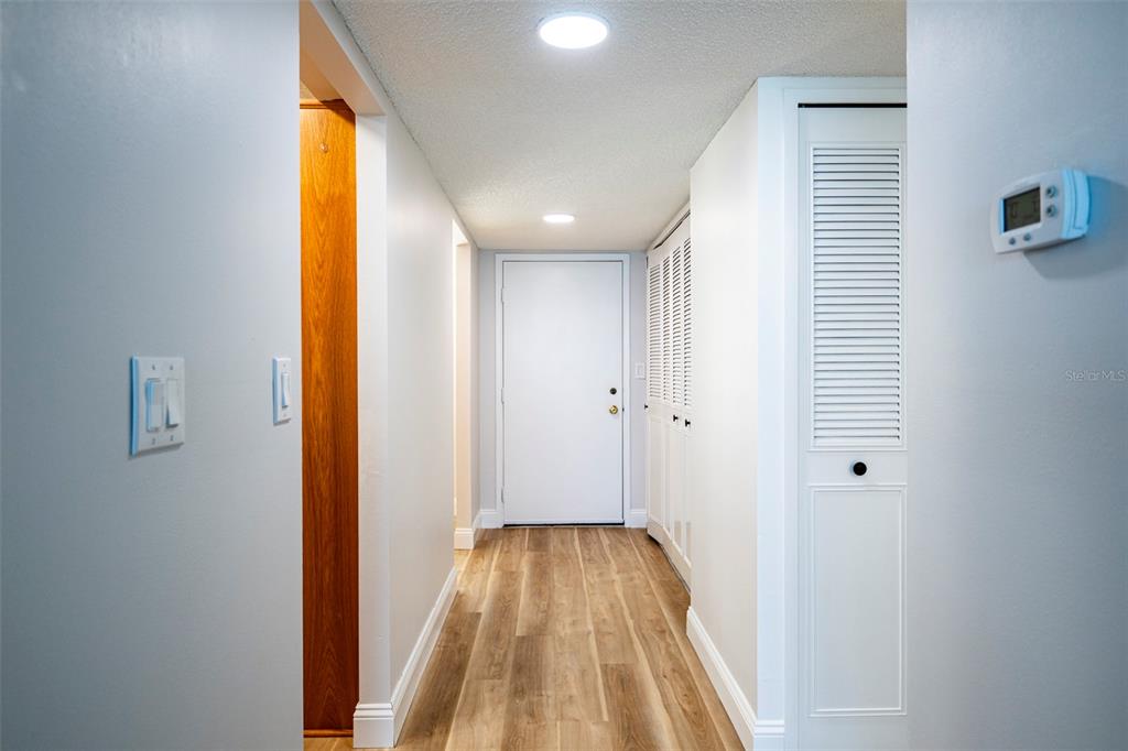 7100 Sunset Way, Unit 810 St. Pete Beach, FL 33706 - Photo 10 of 42 a view of a hallway with wooden floor and a bathroom
