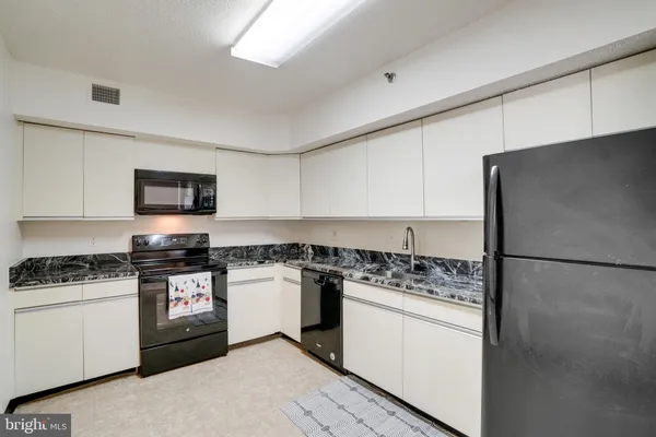 a kitchen with granite countertop white cabinets and white appliances