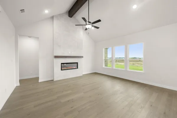 a view of an empty room with a window and wooden floor