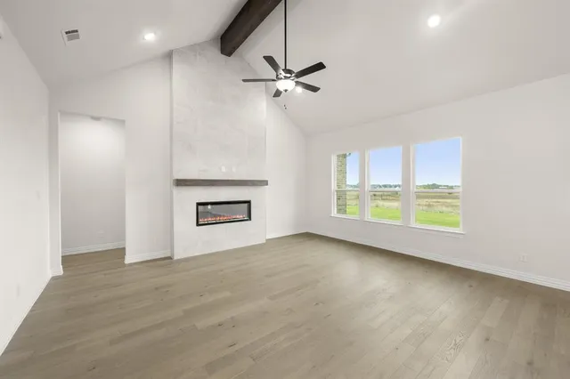 a view of an empty room with a window and wooden floor