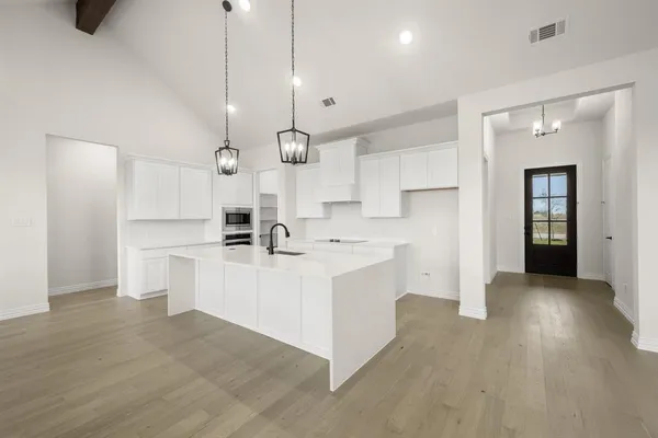 a large white kitchen with white cabinets and stainless steel appliances