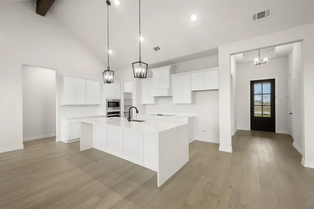 a large white kitchen with white cabinets and stainless steel appliances