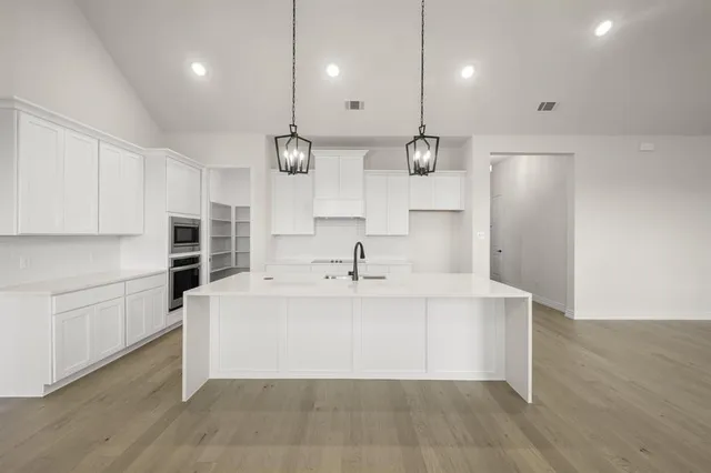 a view of a kitchen with kitchen island a sink stainless steel appliances and cabinets