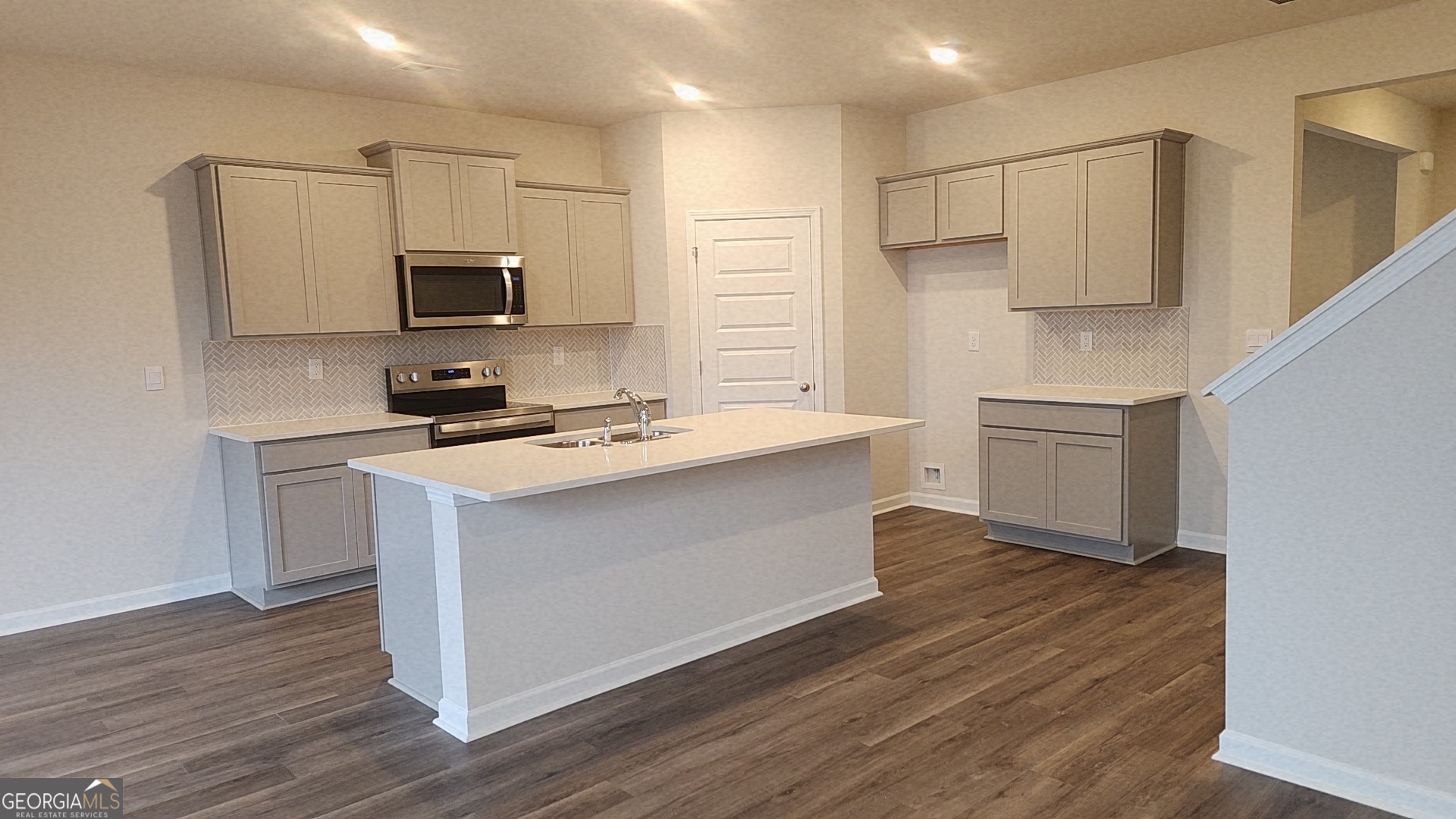 501 Vervain Drive, Unit 174 Locust Grove, GA 30248 - Photo 9 of 33 a kitchen with stainless steel appliances a sink dishwasher a microwave oven and a stove with wooden floor