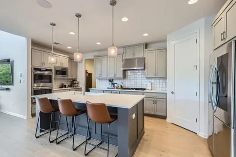 a room with stainless steel appliances kitchen island a dining table and chairs