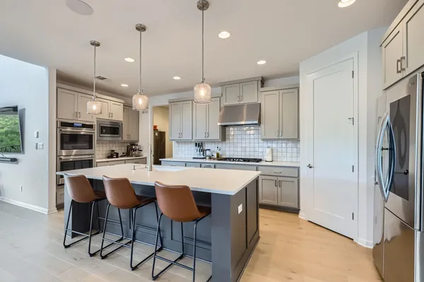 a room with stainless steel appliances kitchen island a dining table and chairs