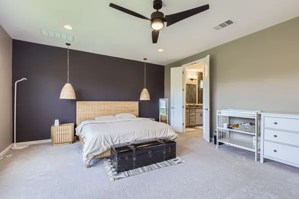 a spacious bedroom with a bed and dresser