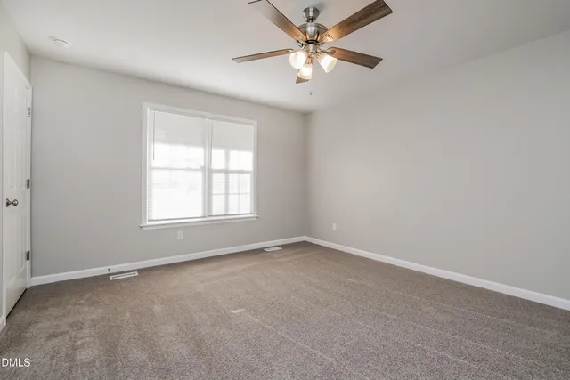 an empty room with a window and a fan