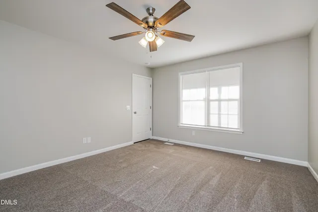 an empty room with a window and a fan