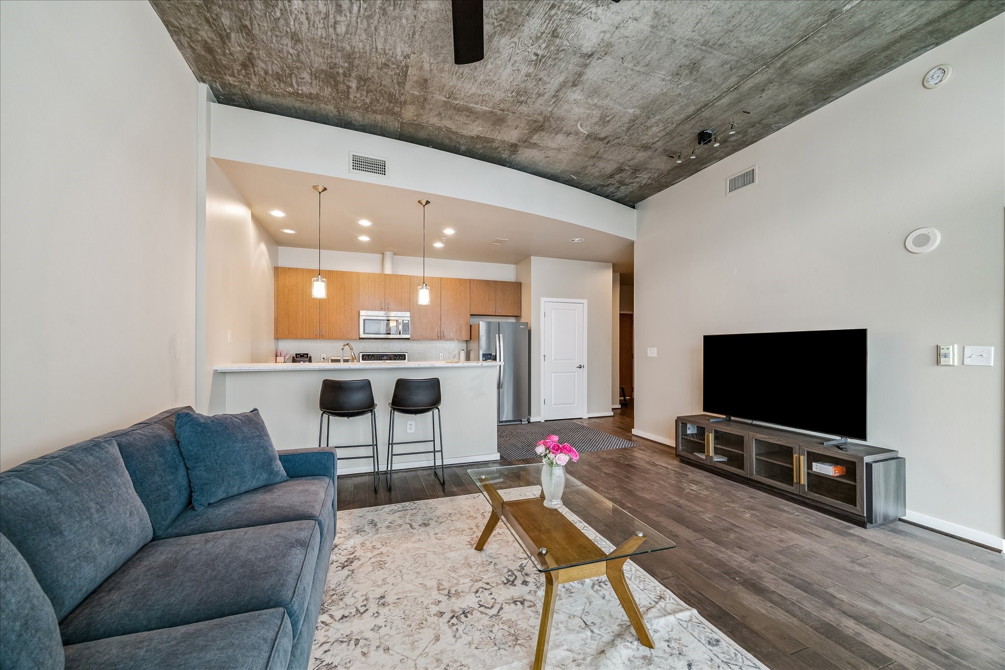 5925 Almeda Road, Unit 12704 Houston, TX 77004 - Photo 2 of 31 Designed for modern living, the spacious living room seamlessly connects to the kitchen and dining areas. Rich engineered hardwood floors, industrial-inspired ceilings, and clean architectural lines offer the perfect blend of style and comfort.