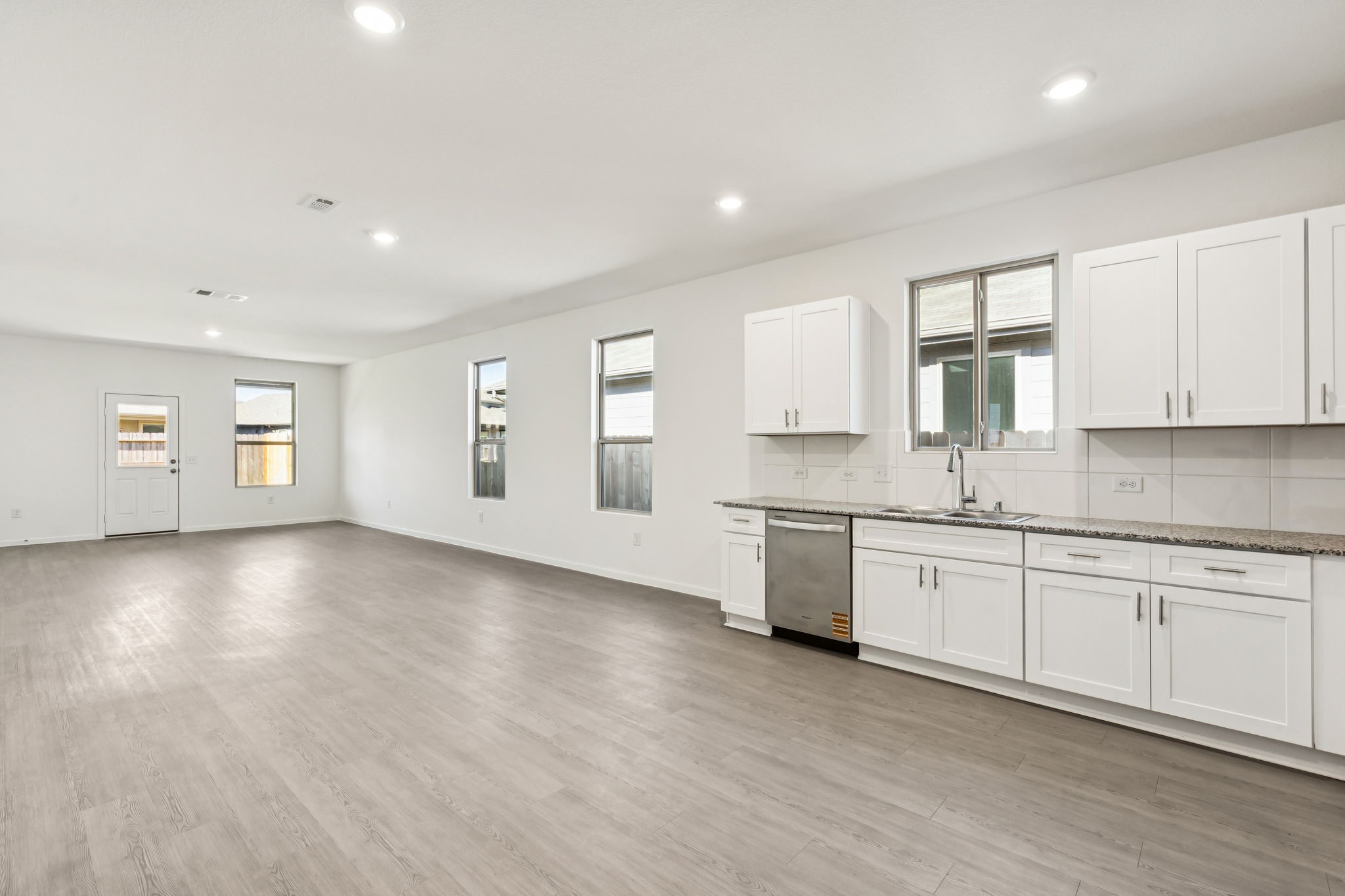14985 Rustic Moon Road Conroe, TX 77302 - Photo 6 of 32 a large kitchen with granite countertop a stove top oven a sink and white cabinets with wooden floor