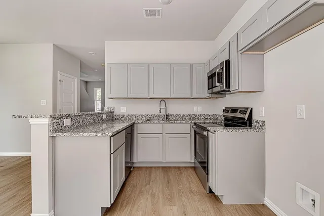 a kitchen with stainless steel appliances granite countertop a stove top oven a sink and dishwasher with wooden floor