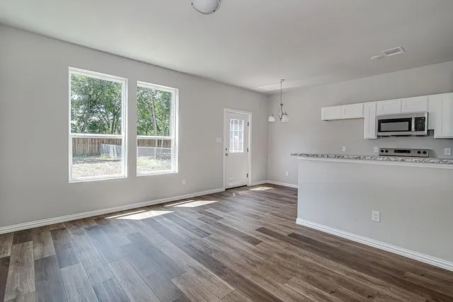 a view of an empty room with wooden floor and a window