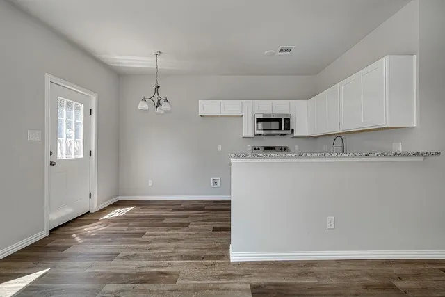 a room with granite countertop cabinets and wooden floor