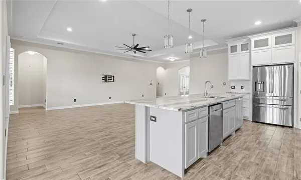 a large kitchen with a large counter top a sink stainless steel appliances and cabinets
