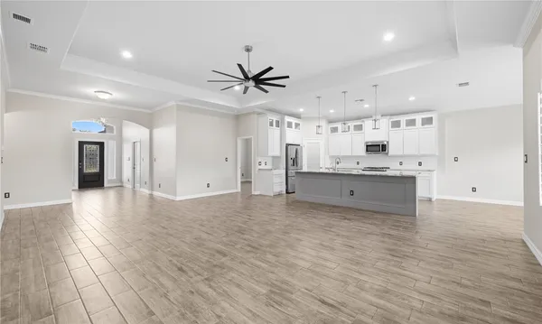 a large white kitchen with kitchen island a stove a sink dishwasher and a refrigerator with wooden floor
